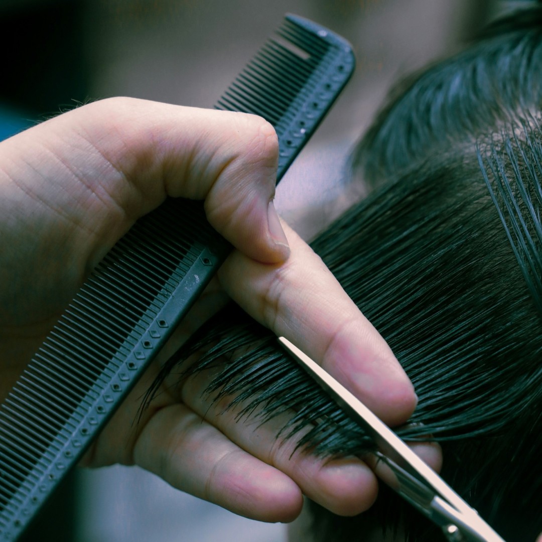 a man cutting hair with scissors and a comb